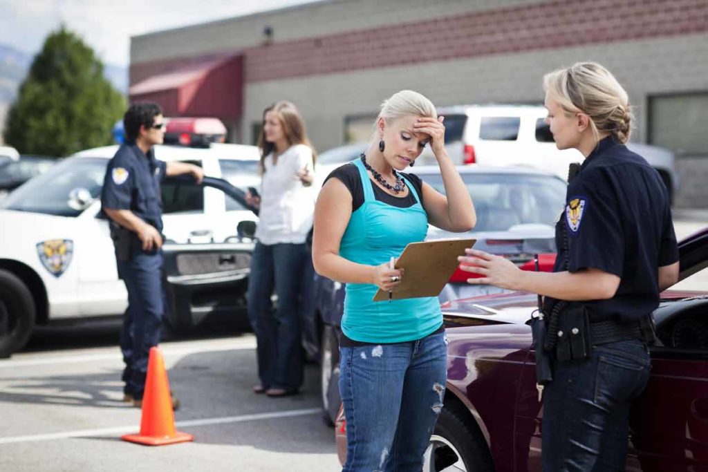 After investigating a car accident scene, a police officer serves an accident report to the at-fault driver